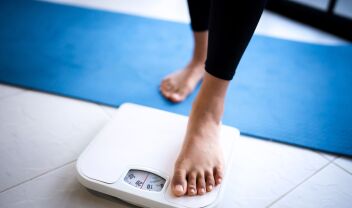 Γυναίκα που στέκεται σε ζυγαριά απογοητευμένη από την επανάκτηση βάρους μετά από επιτυχημένη δίαιτα