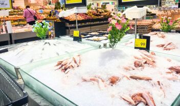 Ιχθυοπώλης σε παραδοσιακή αγορά εξυπηρετεί πελάτες με φρέσκα ψάρια